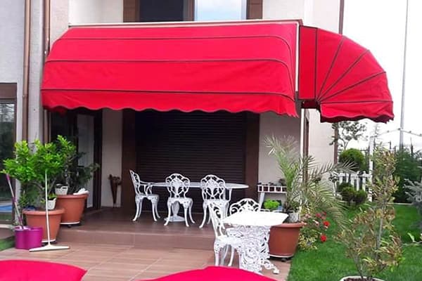 Kafe vitrini önünde açık körüklü tente; kumaş accordion gibi katlanır